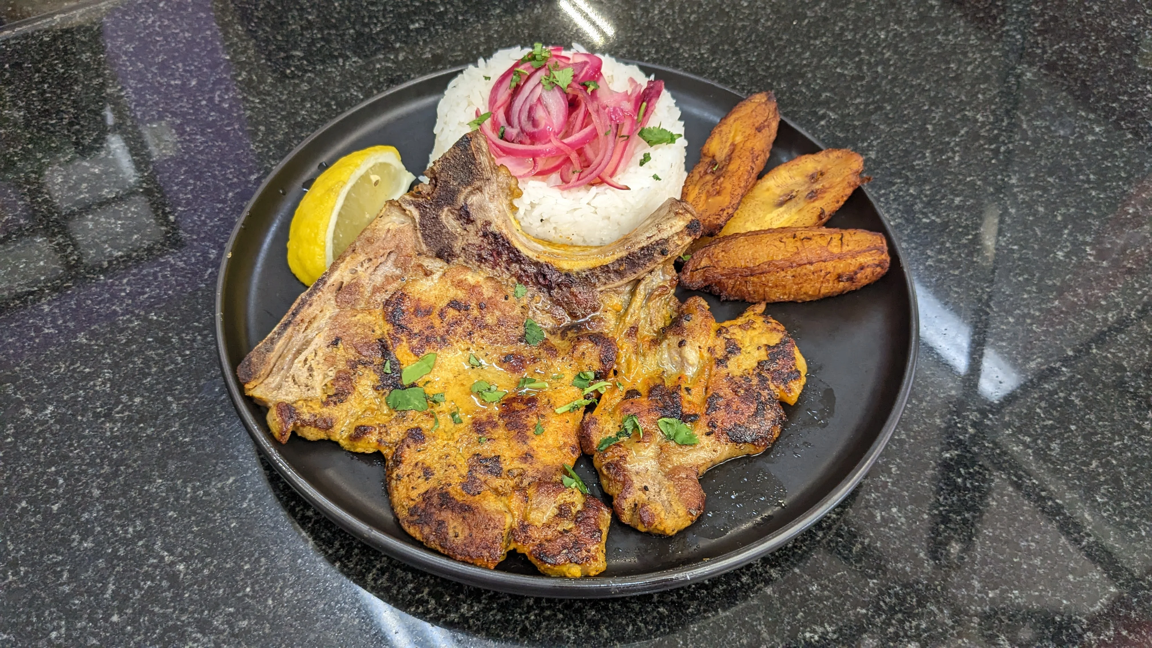 Grilled Dominican chuleta with rice and plantains
