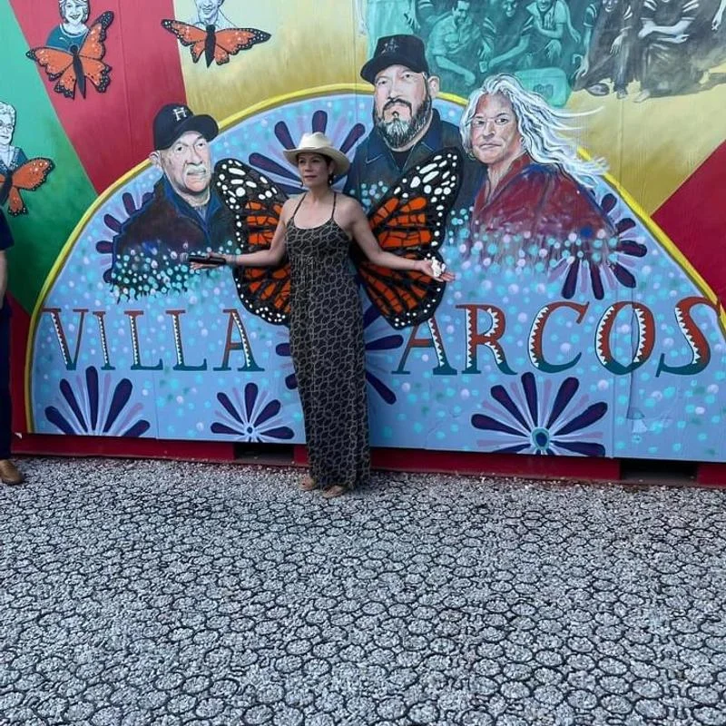 A lady standing in front of the Villa Arcos mural