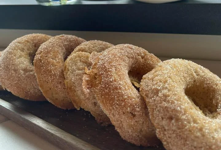 Freshly baked cinnamon sugar donuts on a wooden platter