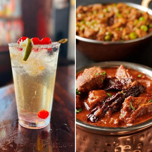 Refreshing cocktail with cherries and lime beside flavorful Indian curry
