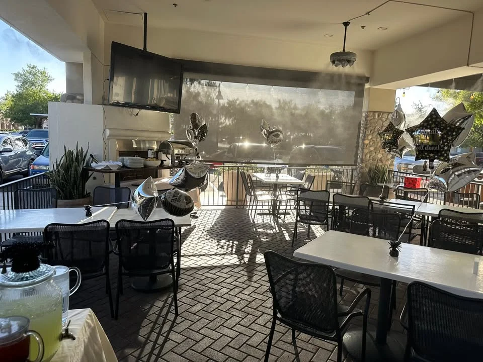 Outdoor dining area with festive balloons and shaded seating