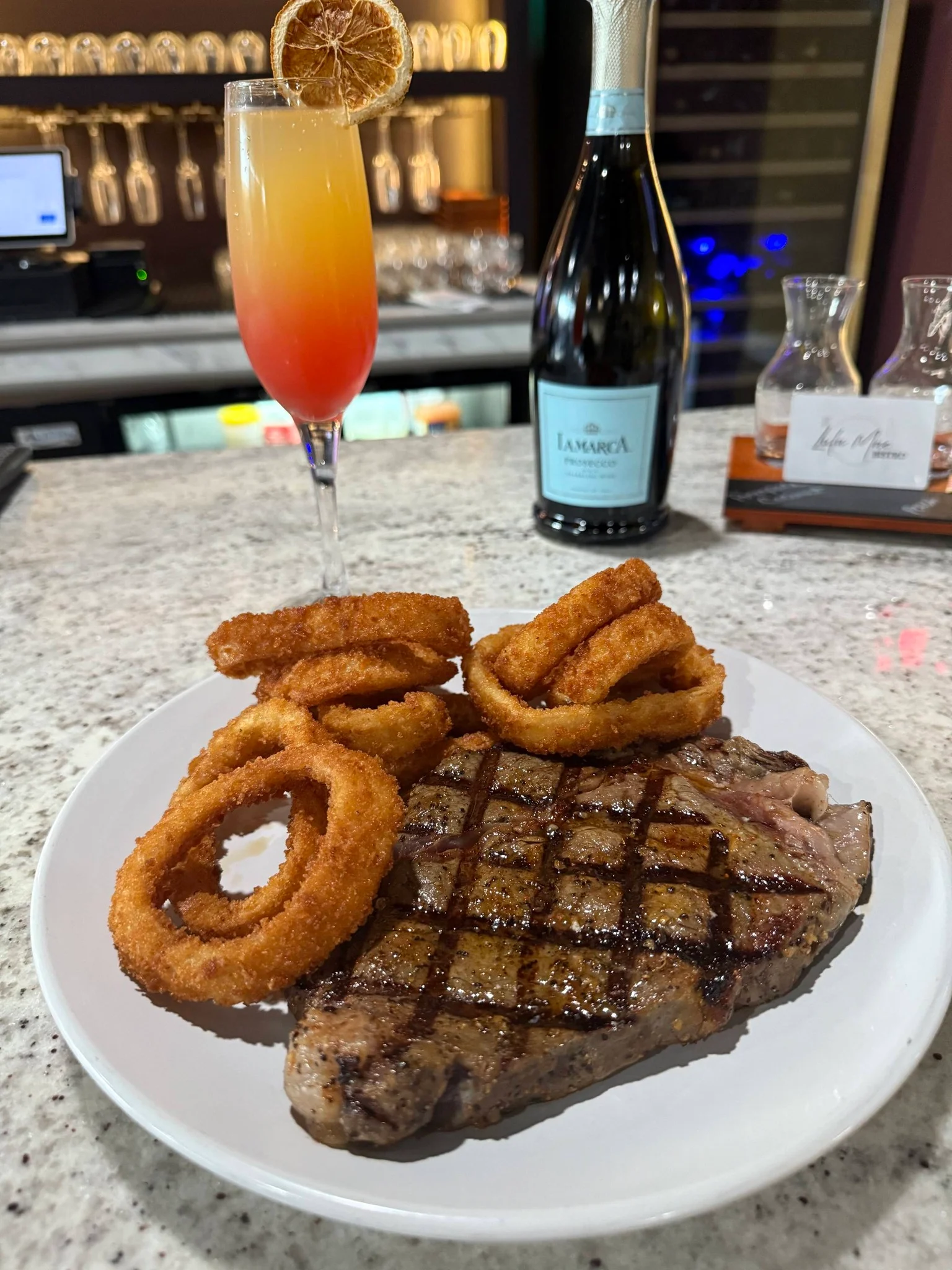 Grilled ribeye steak with onion rings and a colorful cocktail