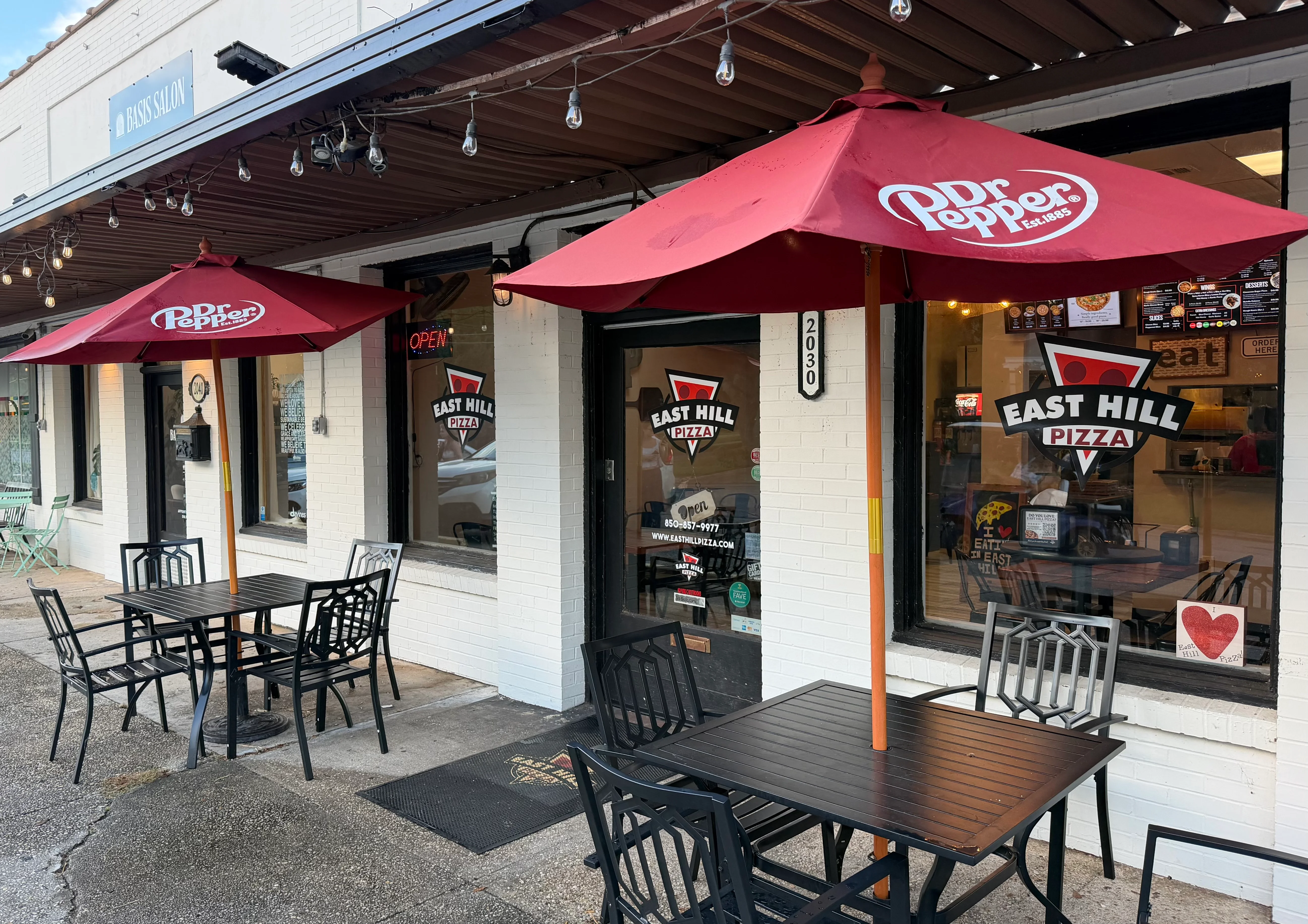 East Hill Pizza restaurant exterior with patio umbrellas and outdoor seating