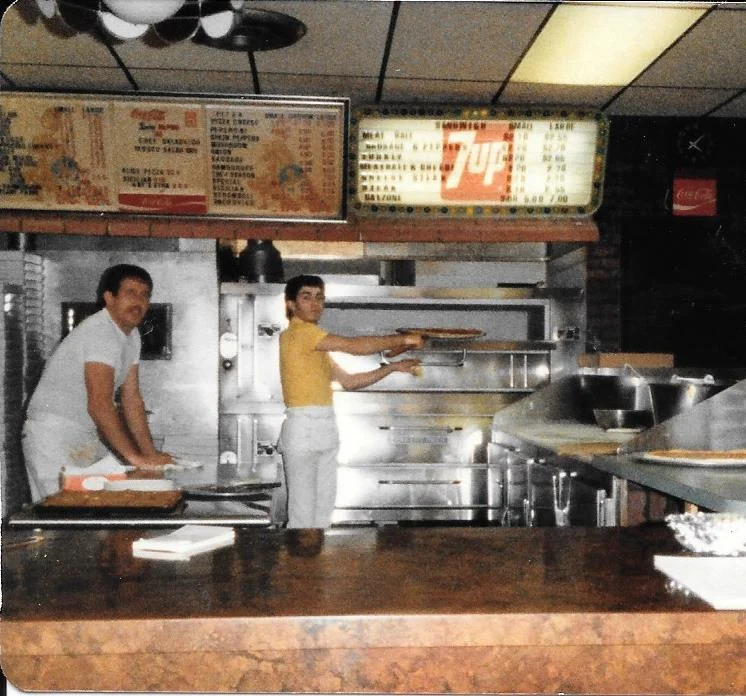 Pizza preparation in a bustling pizzeria kitchen