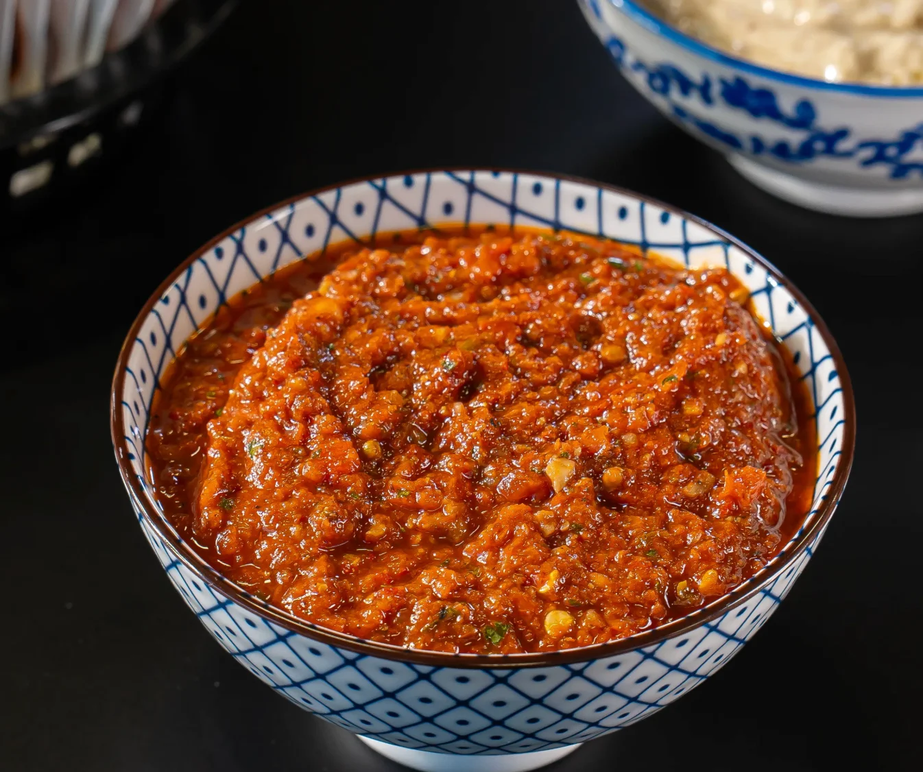 A bowl of red chili sauce with a thick consistency, displaying a rich texture and vibrant color.