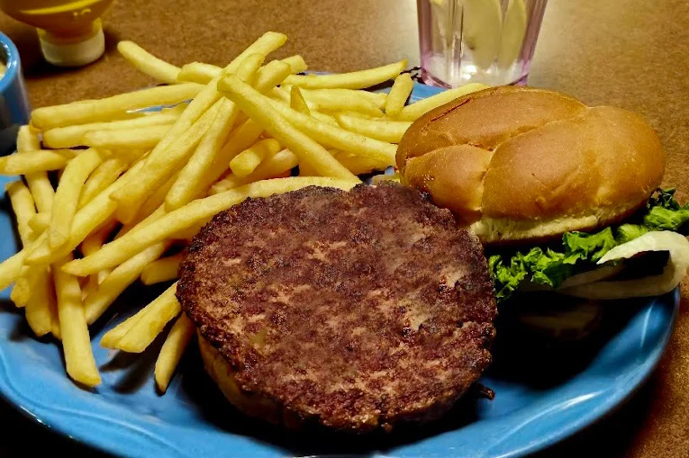 Juicy burger with lettuce, tomato, and cheese on a wooden table