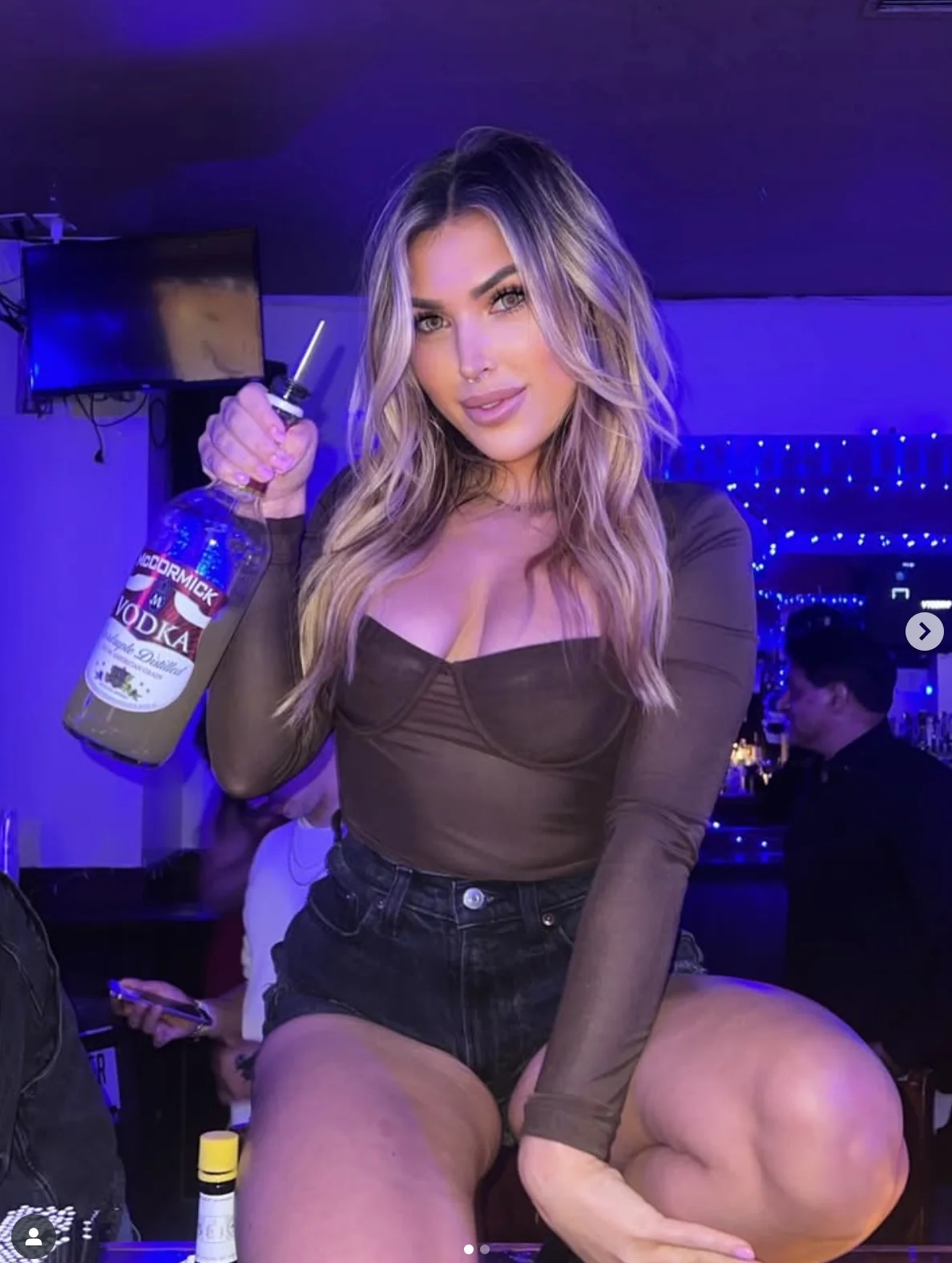 Bartender posing with vodka at a lively bar