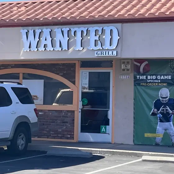 Exterior view of Wanted Grill restaurant with signage and promotional banner