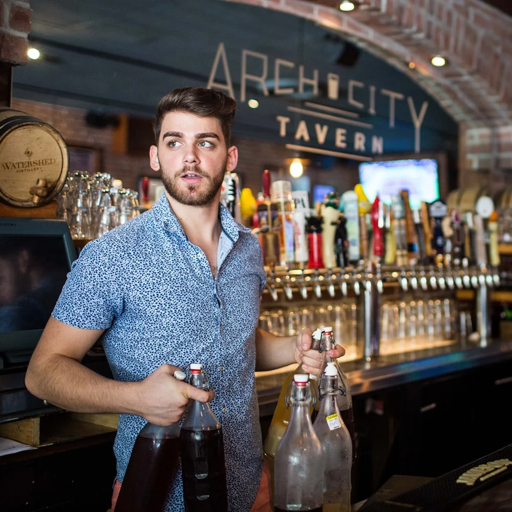 Bartender serving drinks at a lively tavern bar