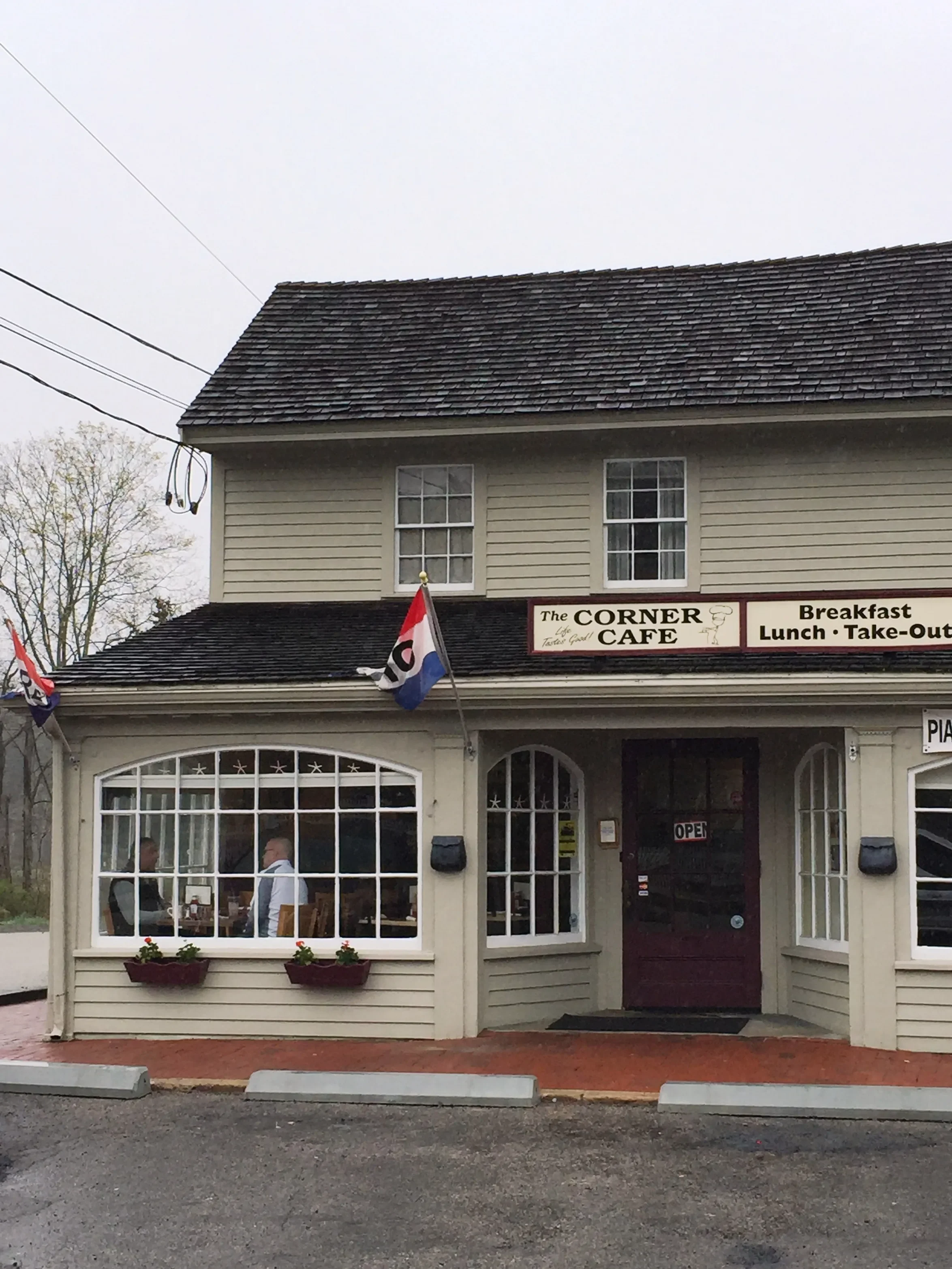 Historic cafe storefront with outdoor flags and visible breakfast and lunch signage