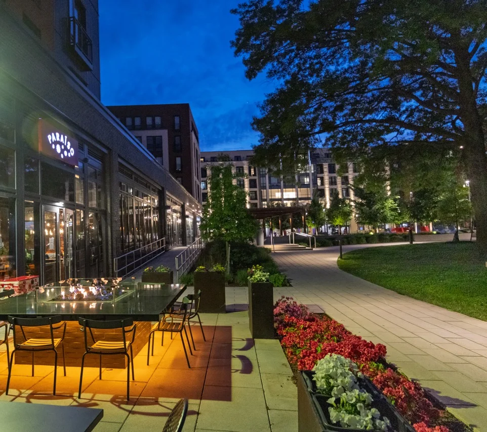 Outdoor dining area with a fire table at dusk near a restaurant.