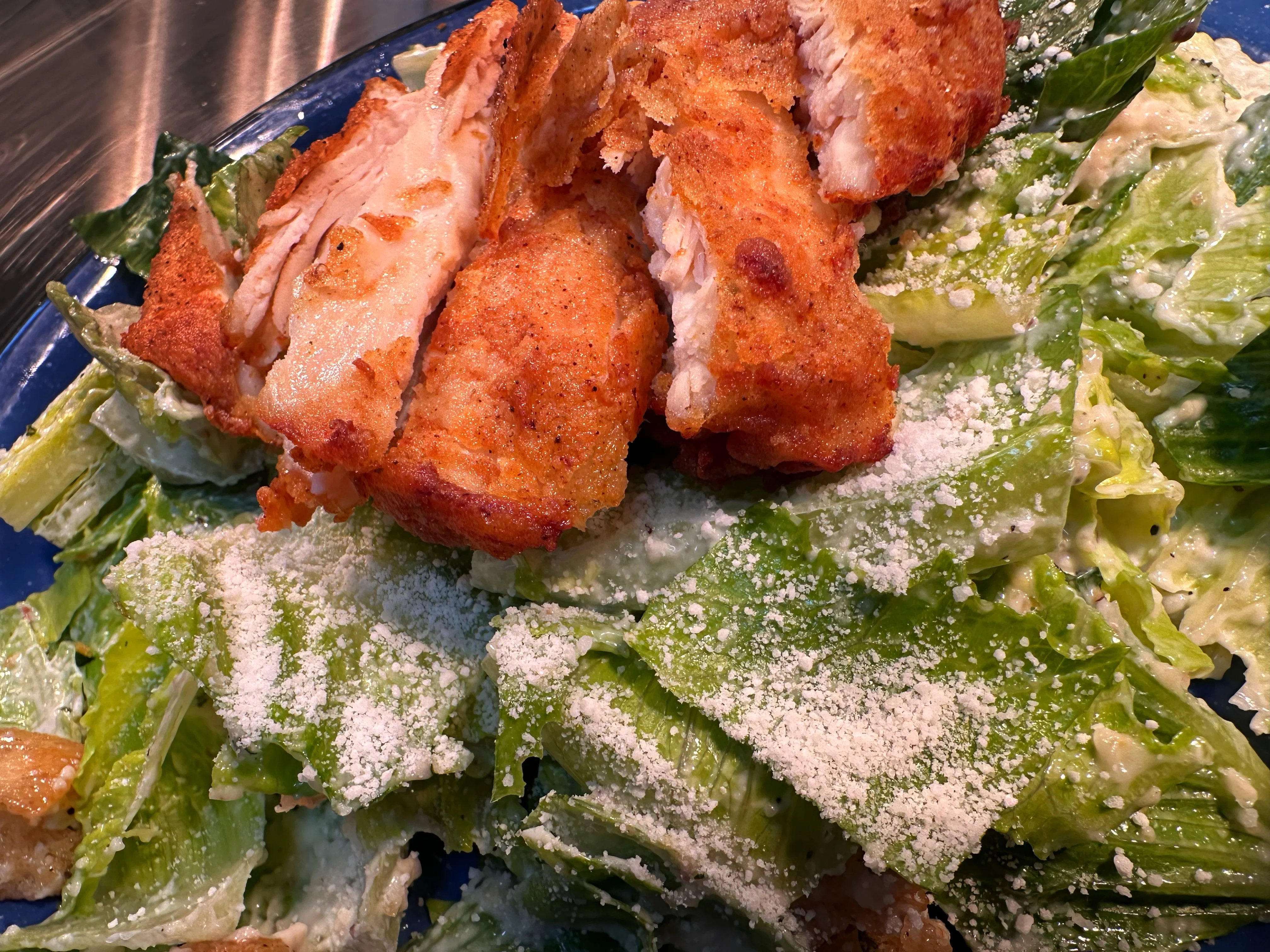 Crispy chicken on a bed of Caesar salad with parmesan cheese.