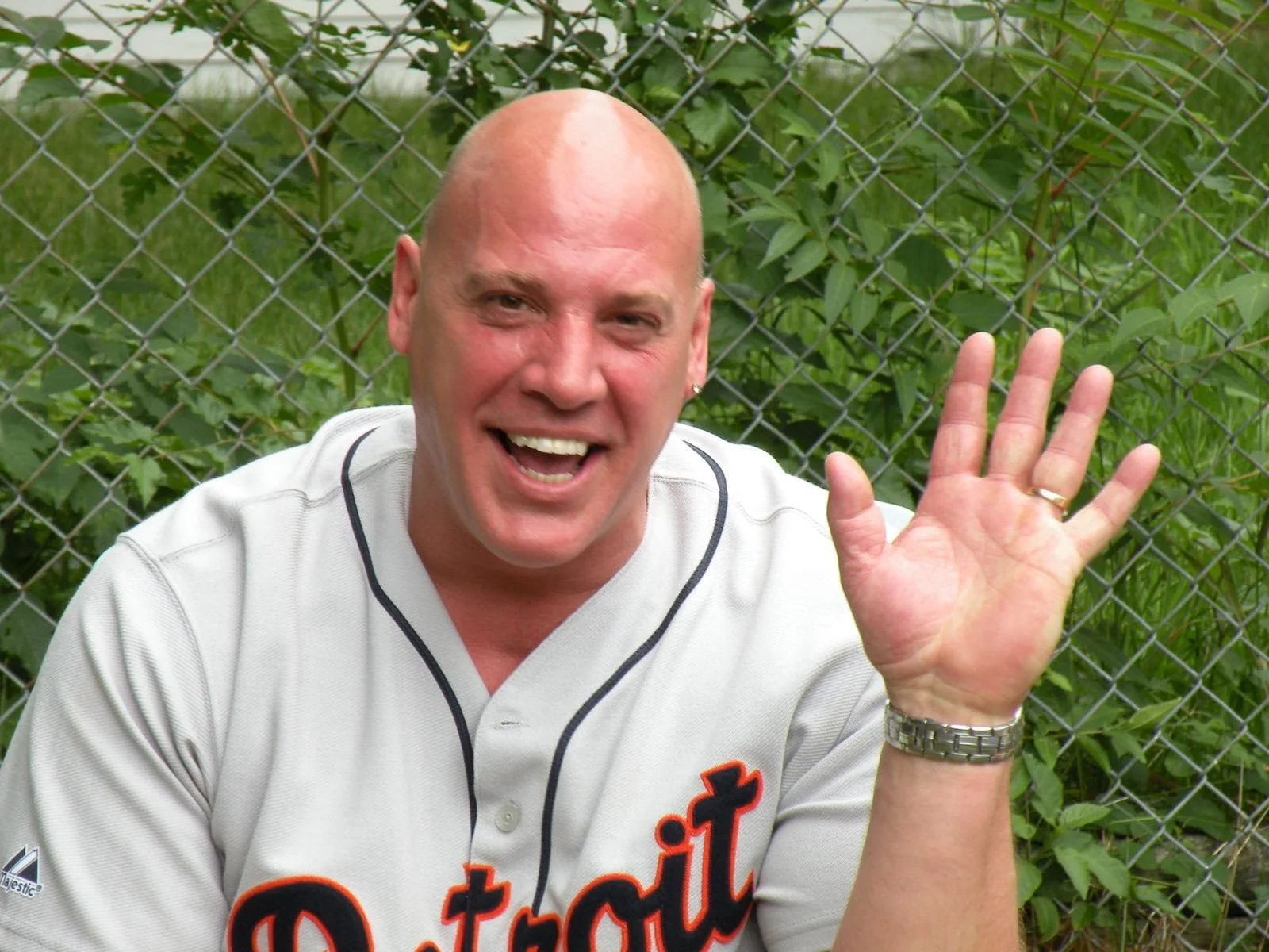 Smiling man waving in a casual outdoor setting
