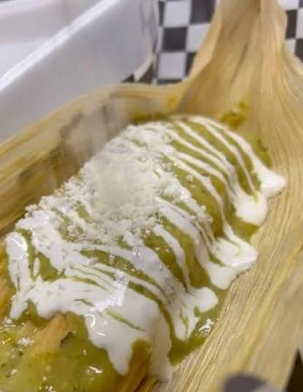 Delicious tamale topped with green sauce and crema