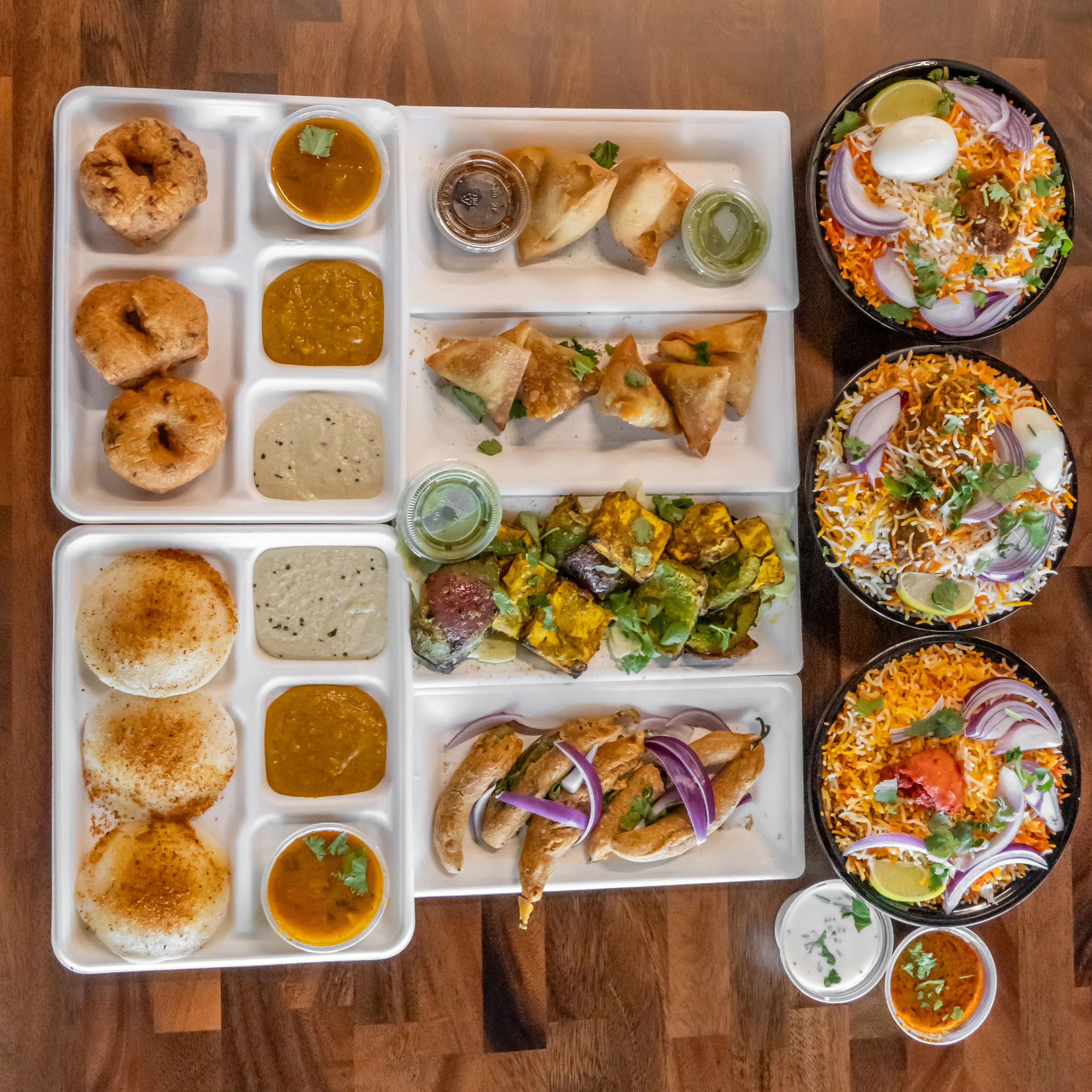 Indian thali with assorted dishes and biryani bowls
