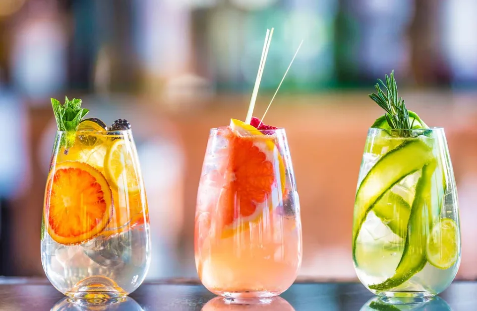 Colorful cocktails garnished with fruits and herbs at a modern bar