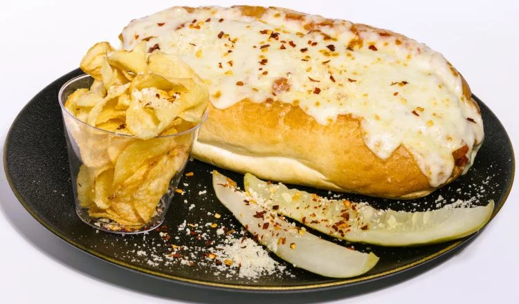 Cheesy Italian sub sandwich with chips and pickles