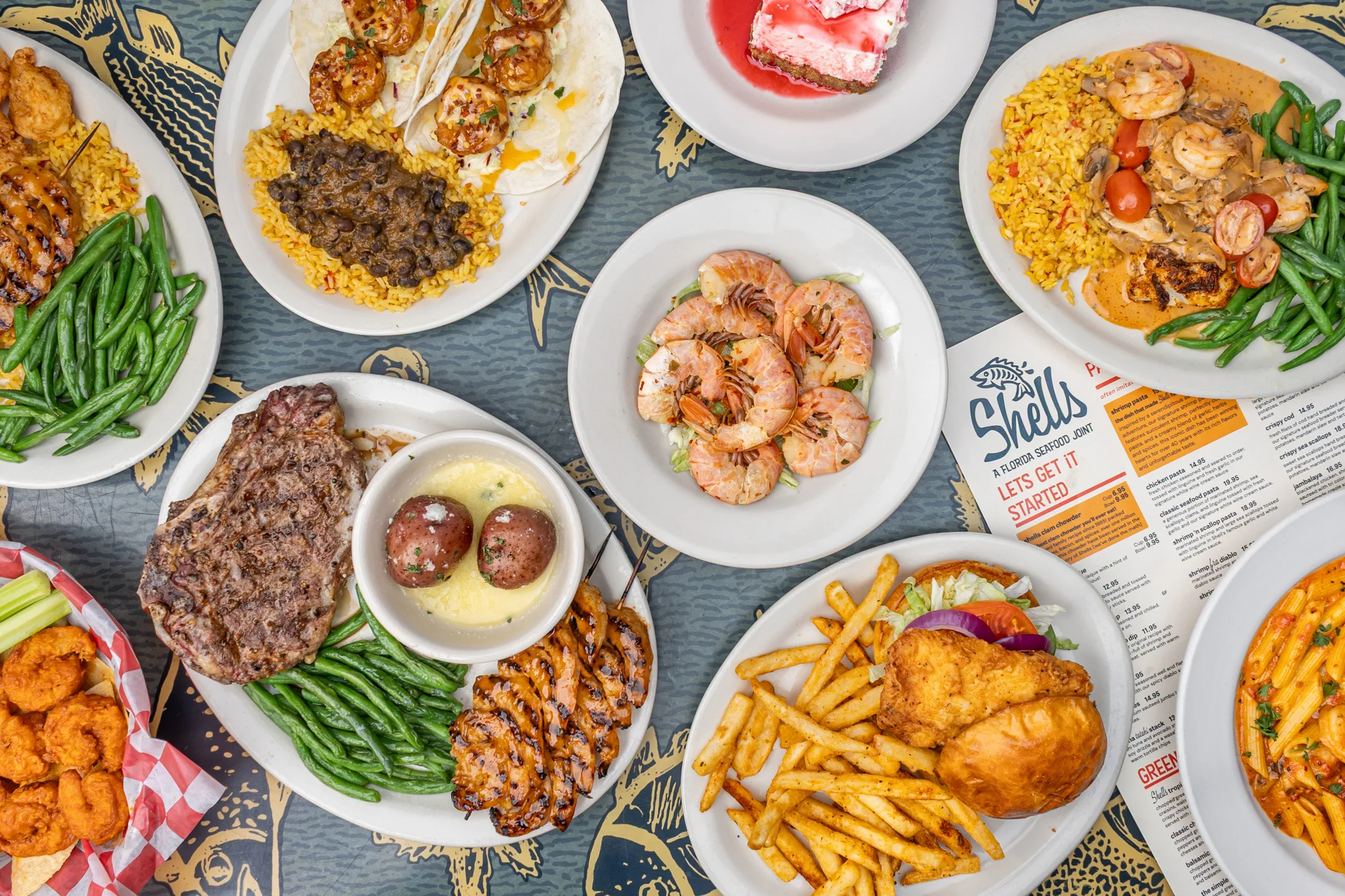 Assorted seafood and grilled dishes on plates in a vibrant restaurant setting