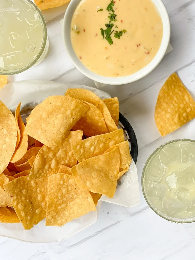 Crispy tortilla chips with queso dip and margaritas