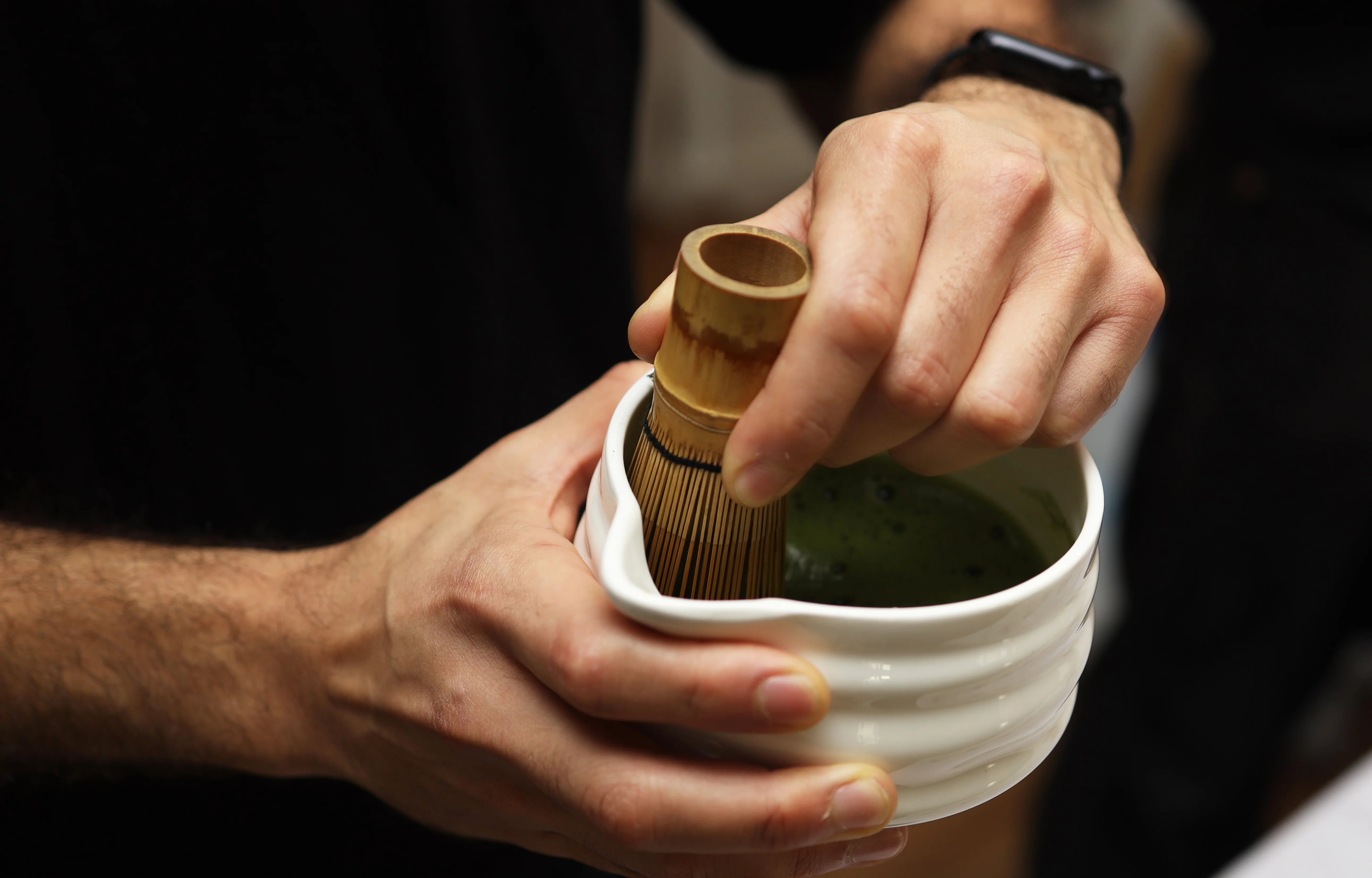 Preparing matcha tea with a bamboo whisk