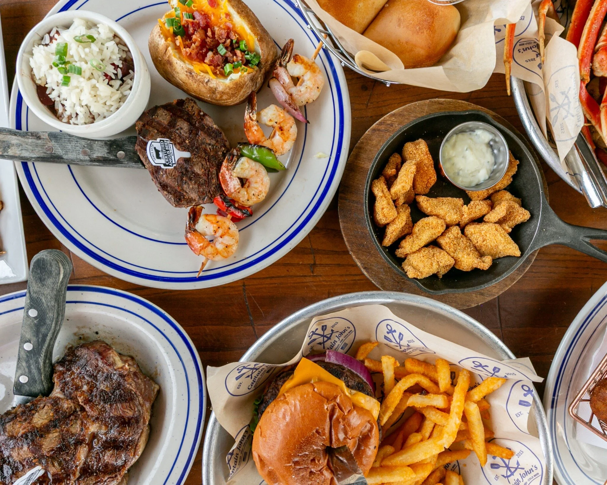 Overhead spread of Captain John’s seafood, steaks, burger and Southern sides