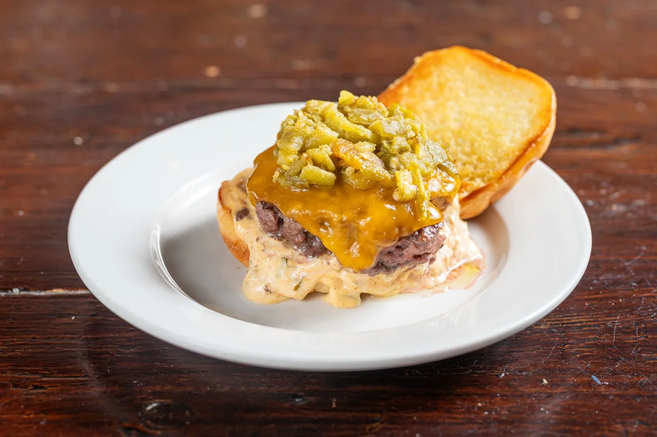 Cheeseburger with green chili topping on a plate