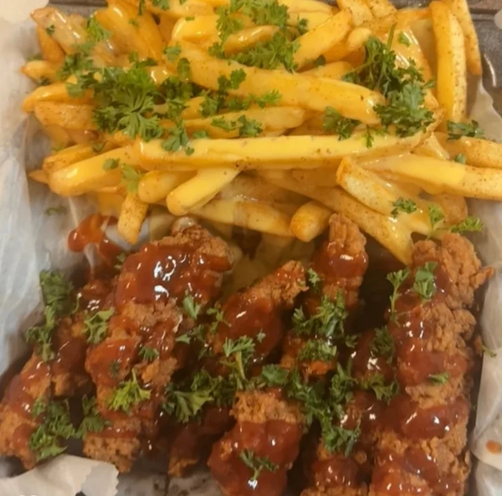 Crispy fried chicken strips topped with barbecue sauce, served with golden fries and garnished with parsley.