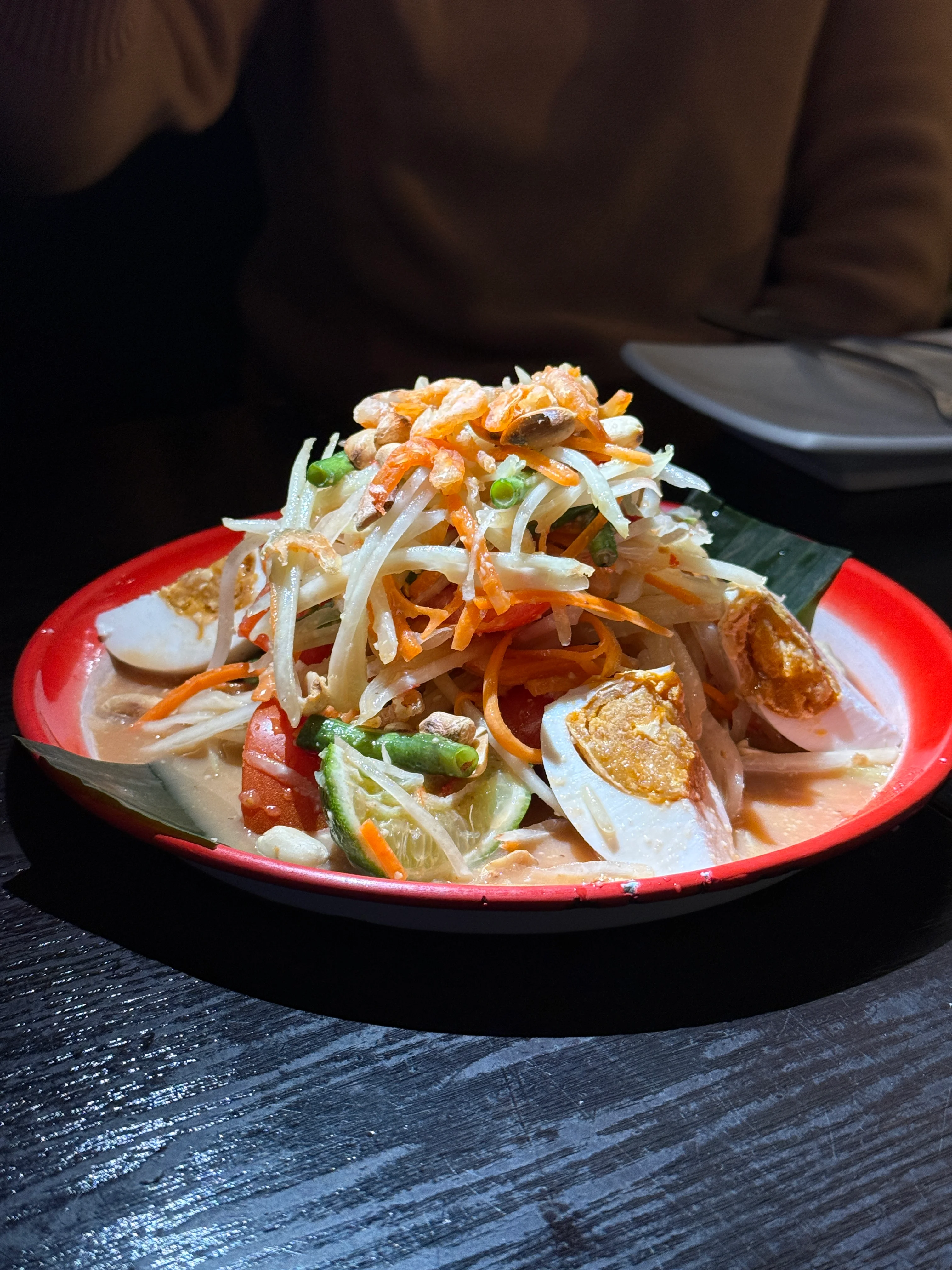 Thai green papaya salad served on a red plate