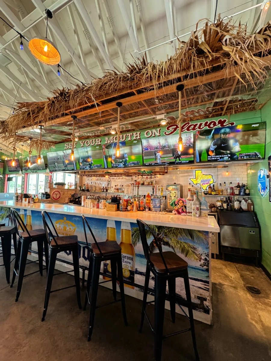 Colorful bar with drinks and TVs in a vibrant restaurant setting.