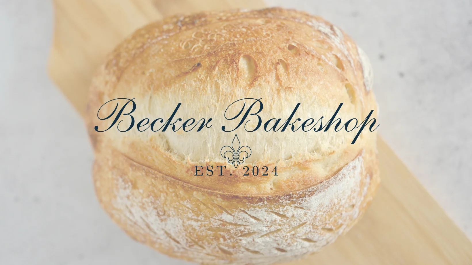 Artisan sourdough boule on a wooden board with bakery branding