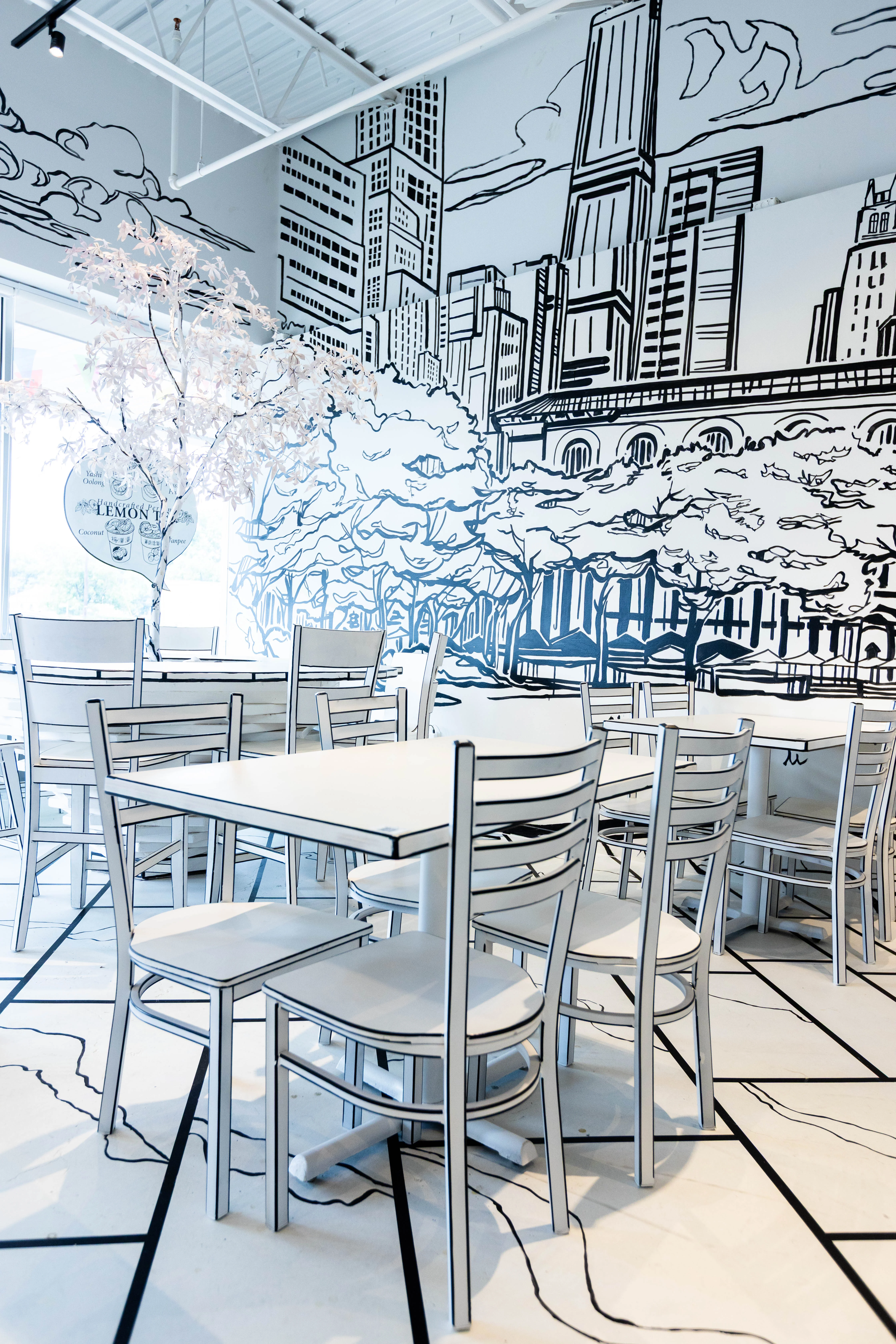 The Chopsticks Charm logo on a feature wall with a large, stylized tree mural, showcasing the restaurant's unique 2-D design.