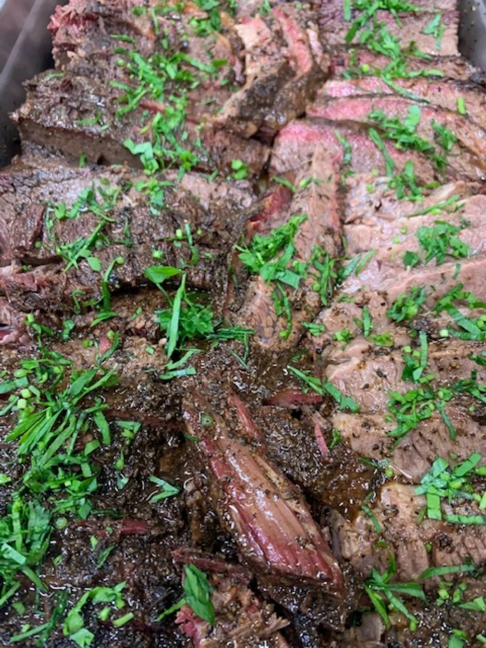 Sliced Brazilian picanha topped with fresh herbs