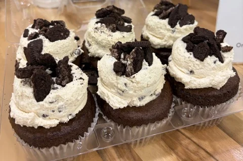 Assorted gourmet cupcakes in a clear container