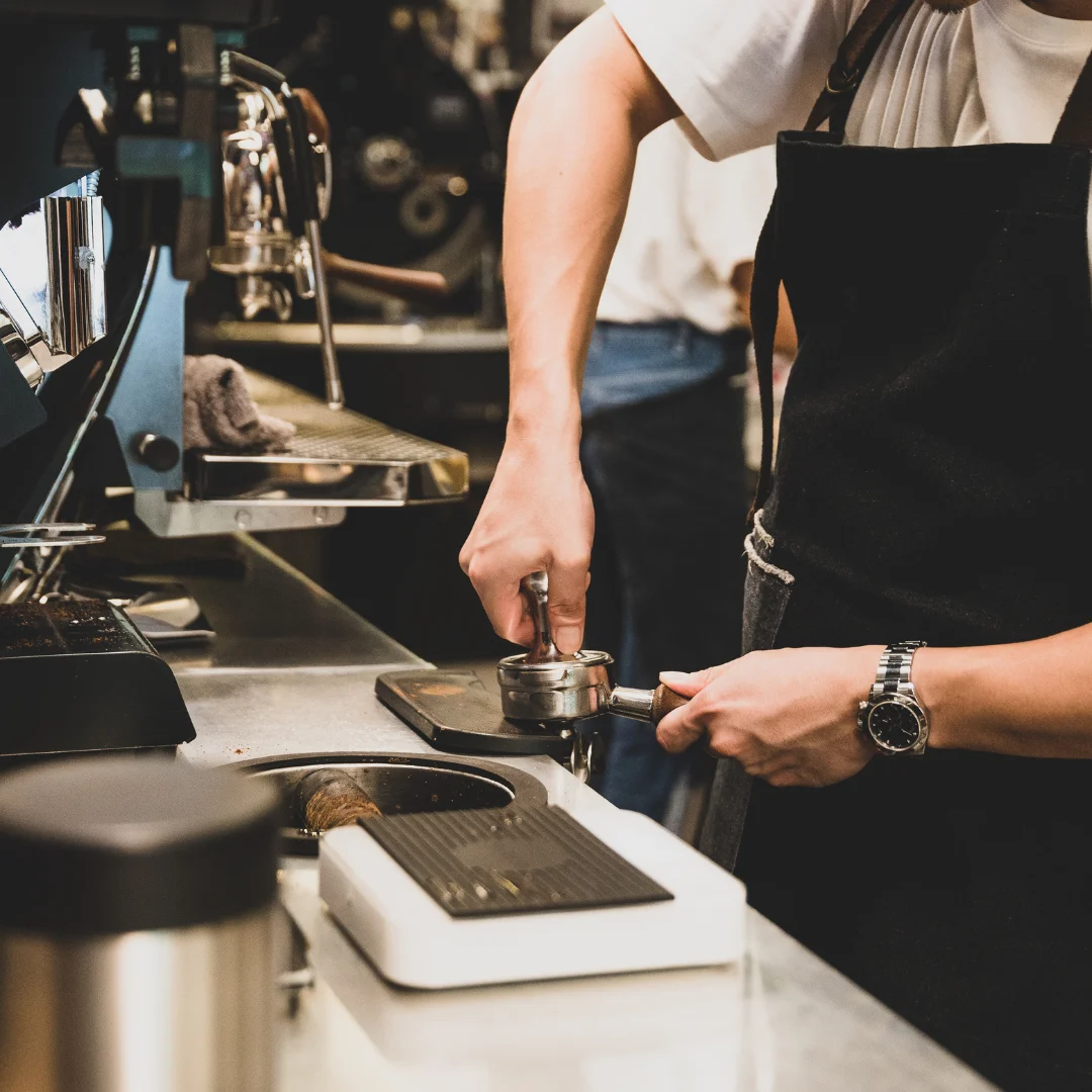 Barista preparing espresso with a portafilter in a coffee shop