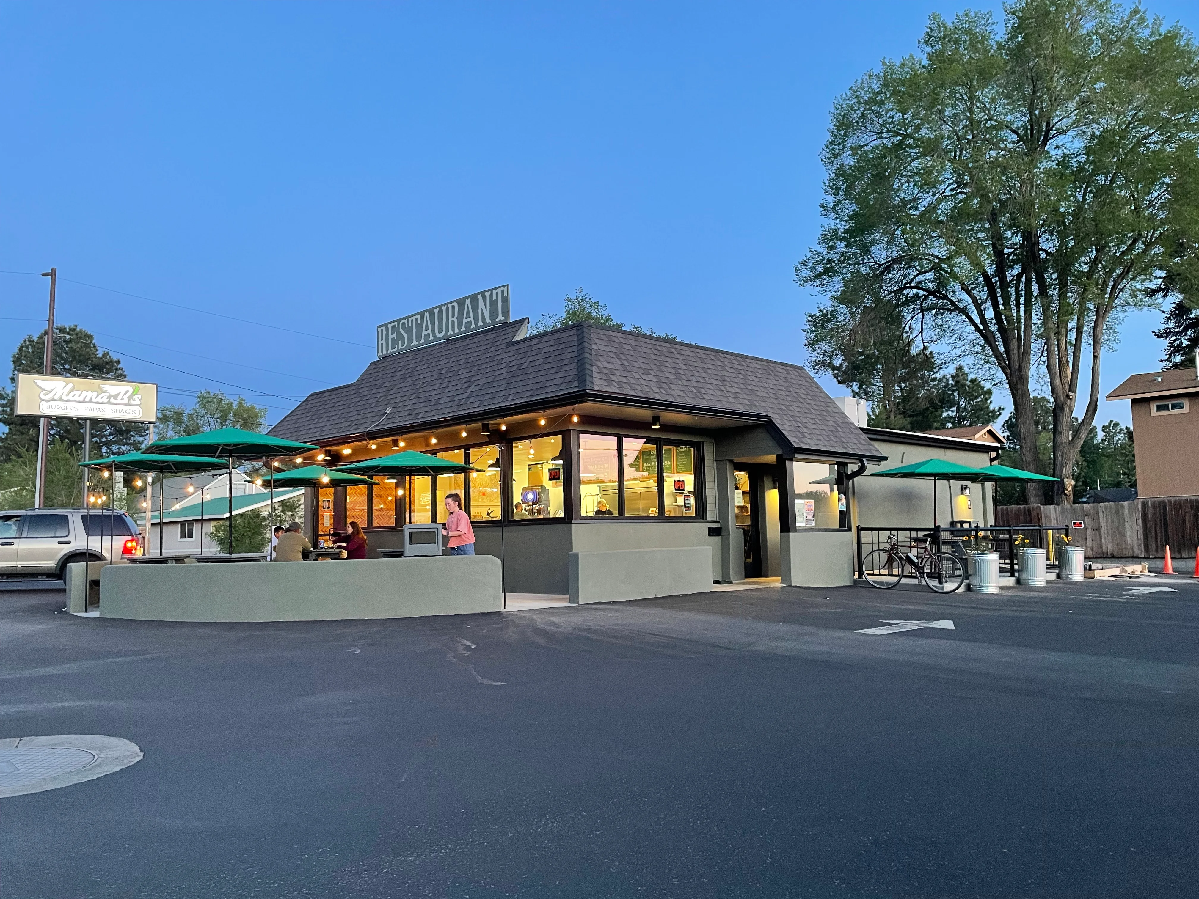 Charming restaurant exterior with outdoor seating and green umbrellas