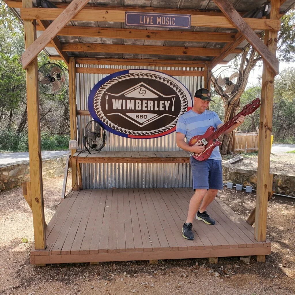 Person playing guitar on a stage at Wimberley BBQ restaurant