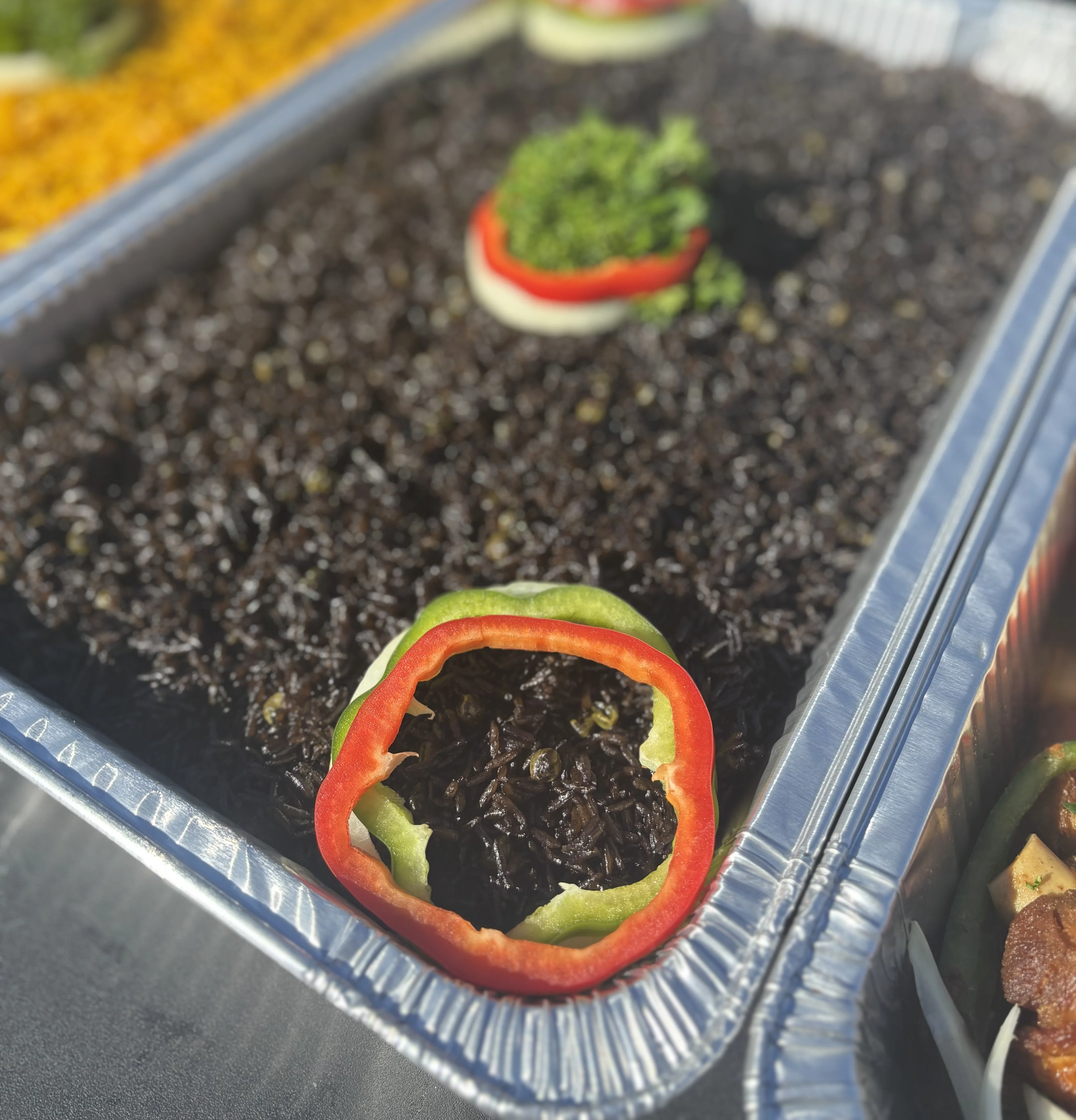 A close-up view of a dish featuring black rice, garnished with bell peppers and herbs for decoration.