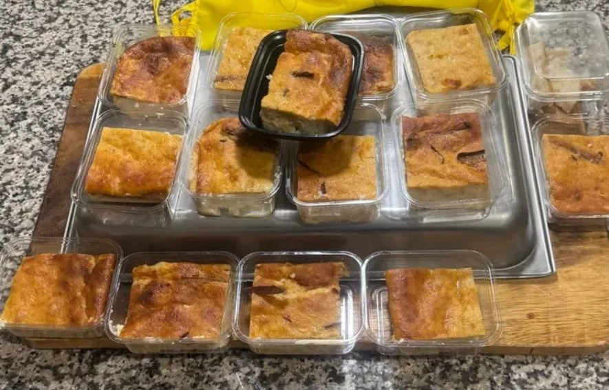A selection of baked desserts arranged in individual containers with some stacked on top of a tray.