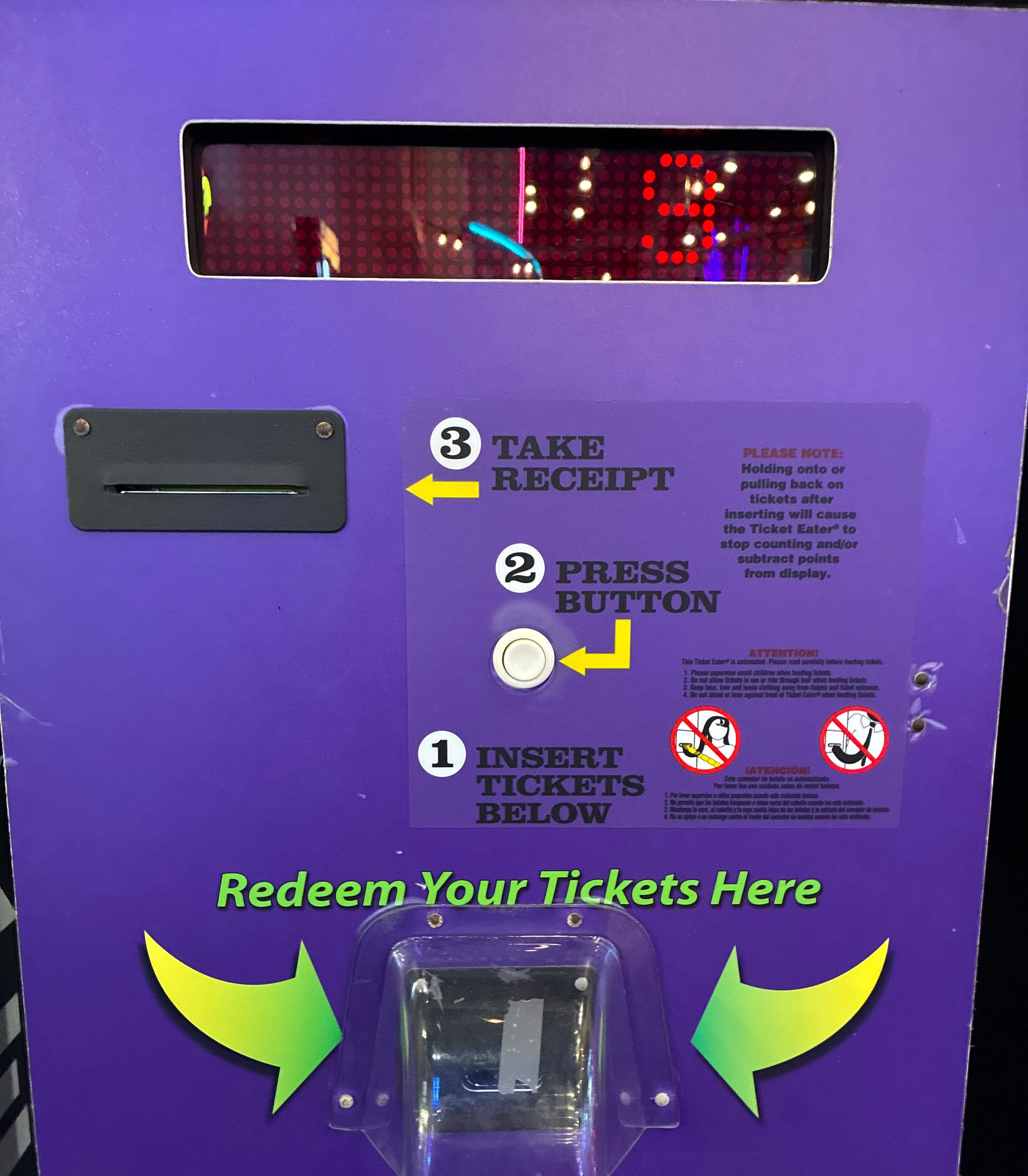 Purple ticket redemption kiosk with instructions and illuminated display