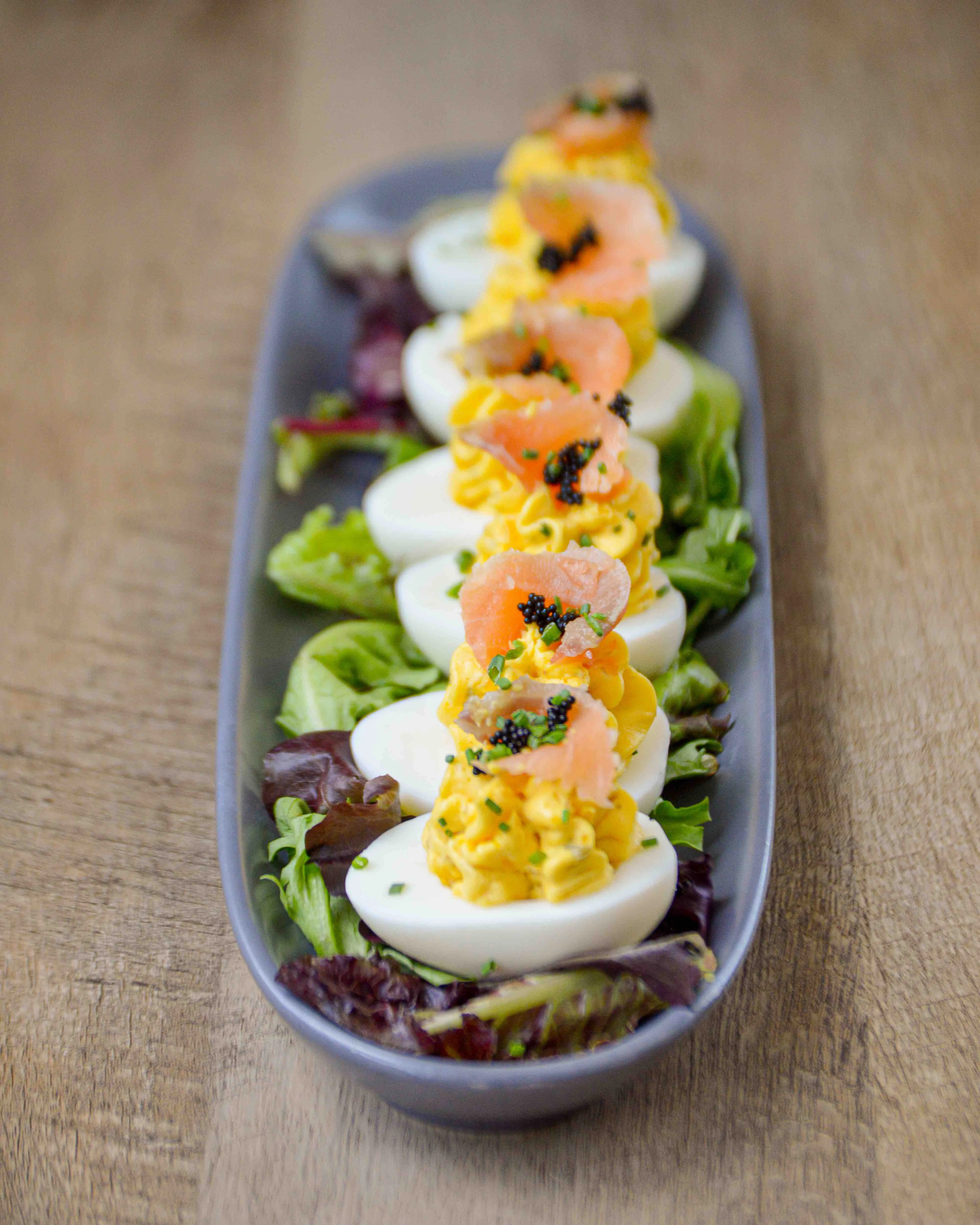 6 deviled eggs sit in a line, garnished with caviar