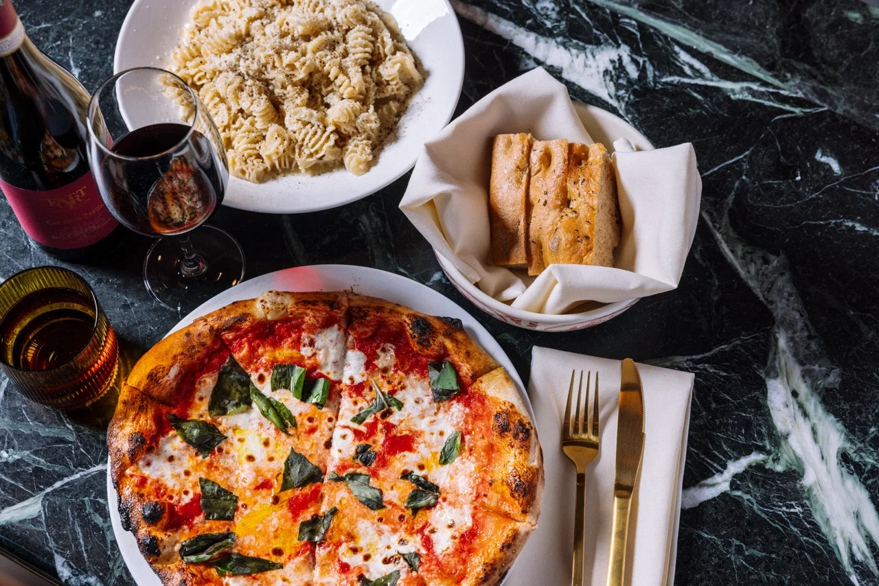 Italian dining spread with Neapolitan Margherita pizza, pasta, bread, and red wine