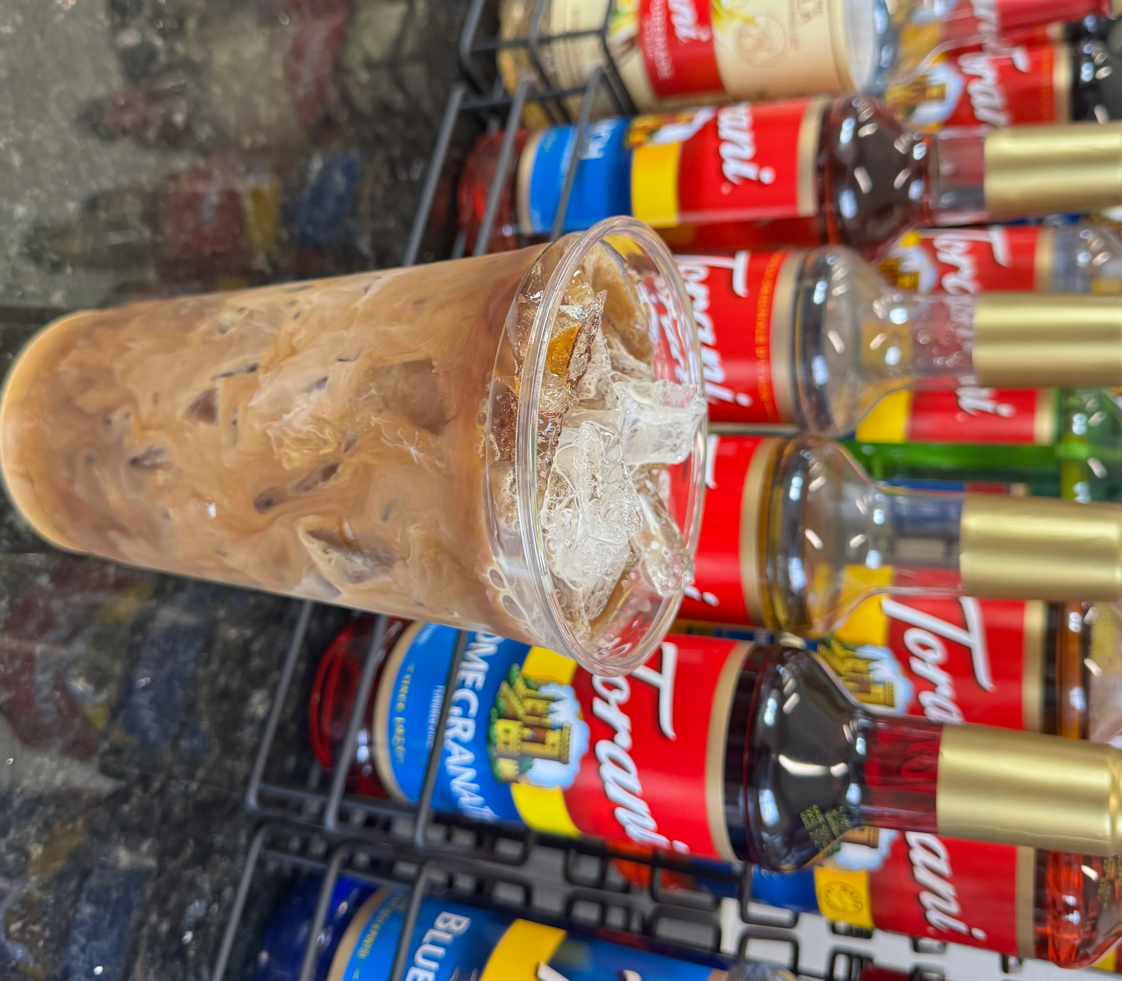Iced coffee drink with Torani syrups in the background