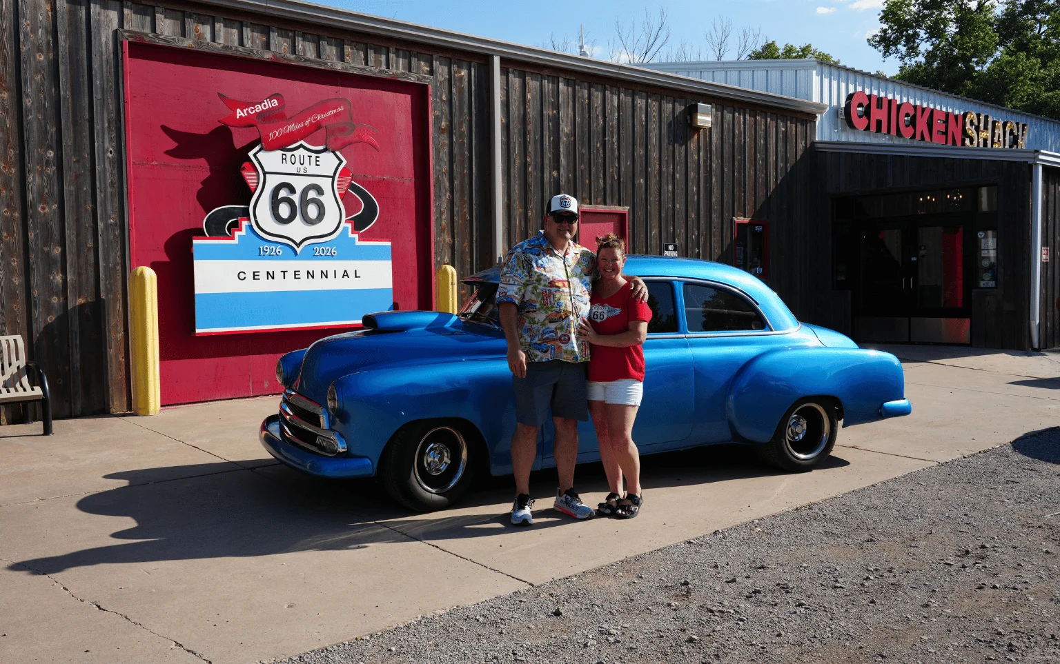 Couple posing with a classic blue car at Route 66 Chicken Shack