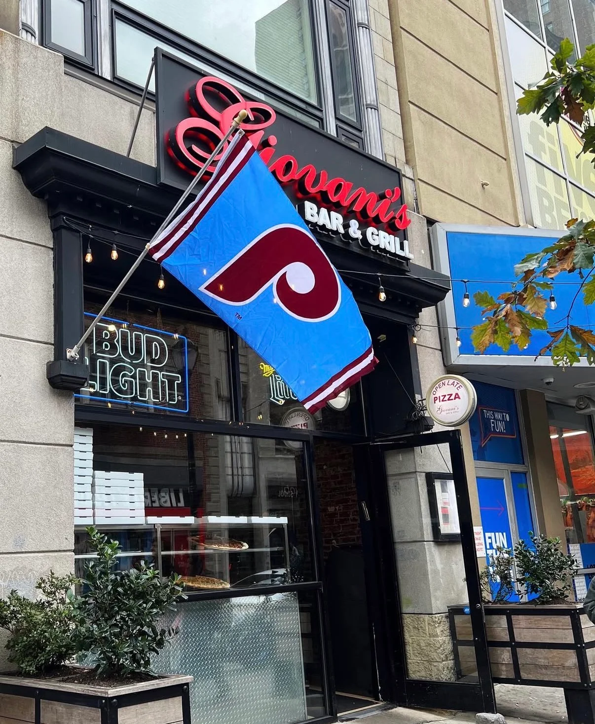 An outdoor view of a bar and grill establishment featuring a prominent sign and a flag.