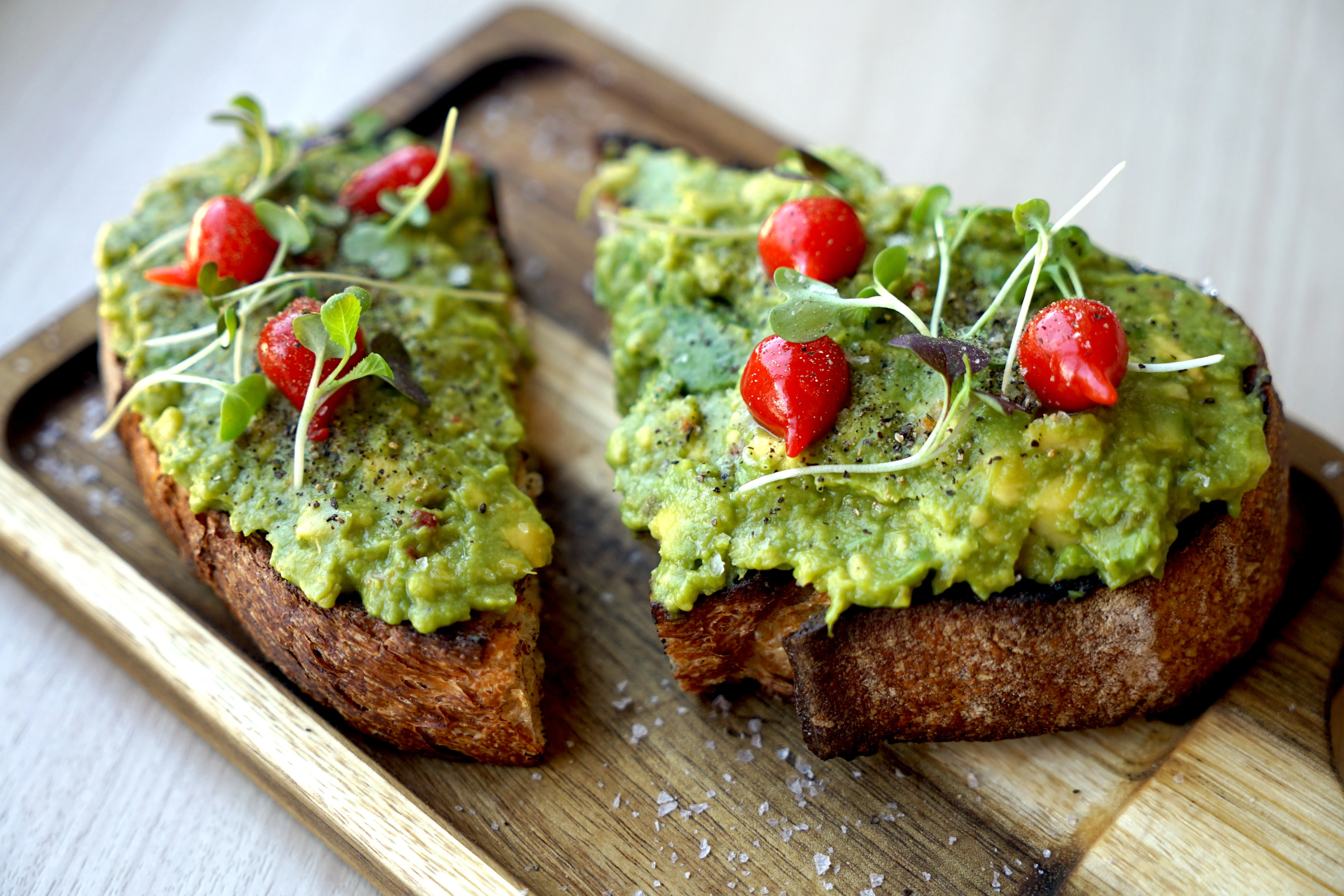 Avocado toast topped with cherry tomatoes and microgreens