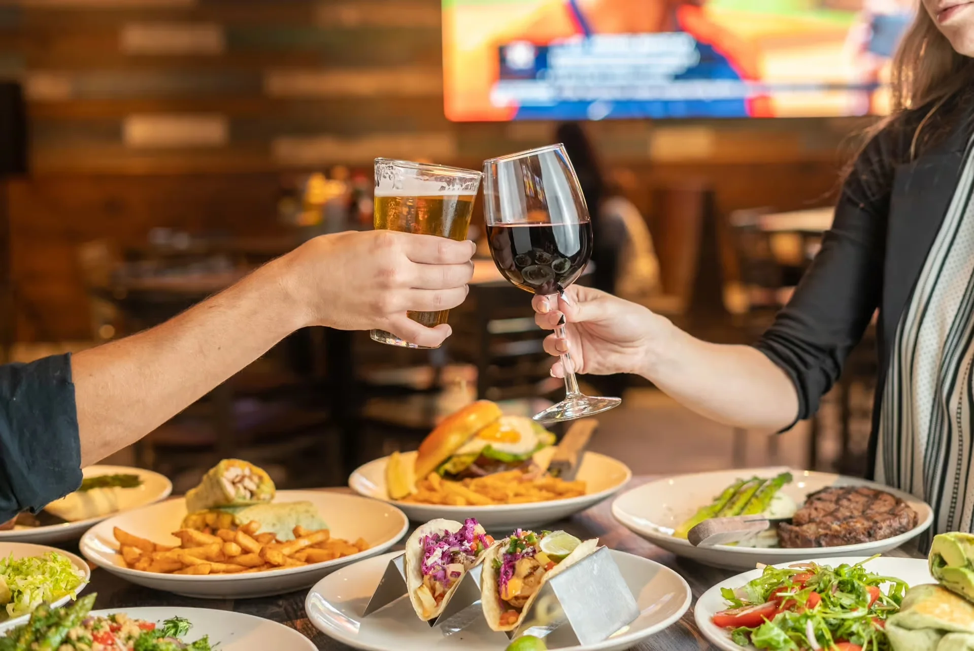 Cheers with beer and red wine in a vibrant restaurant setting