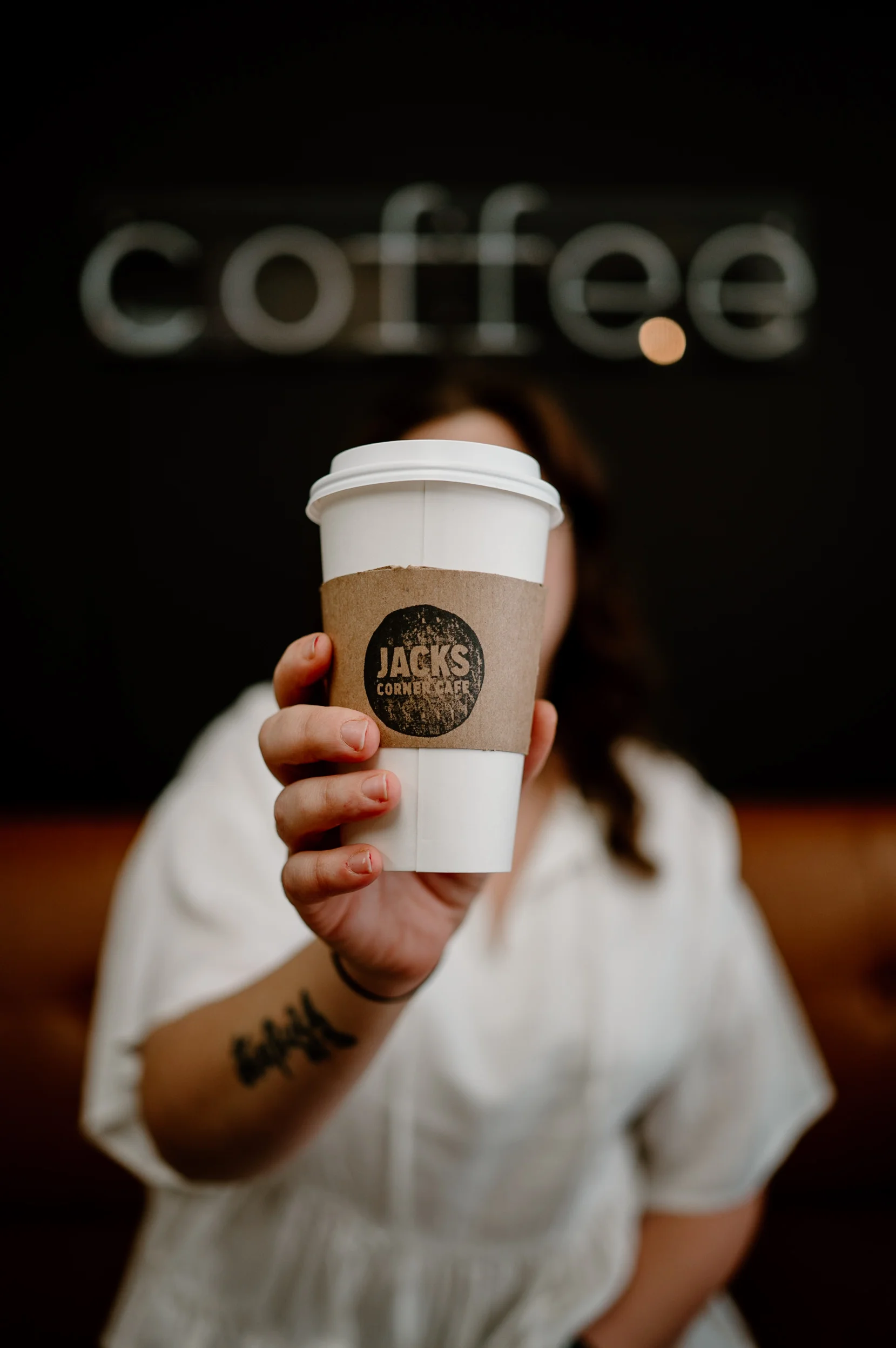 Coffee cup from Jack's Corner Café held by a customer