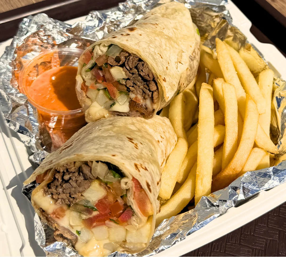 Two burritos with beef and vegetables, served with fries and sauce.
