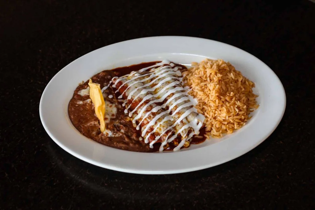 Plate of enchiladas topped with sauce and sour cream