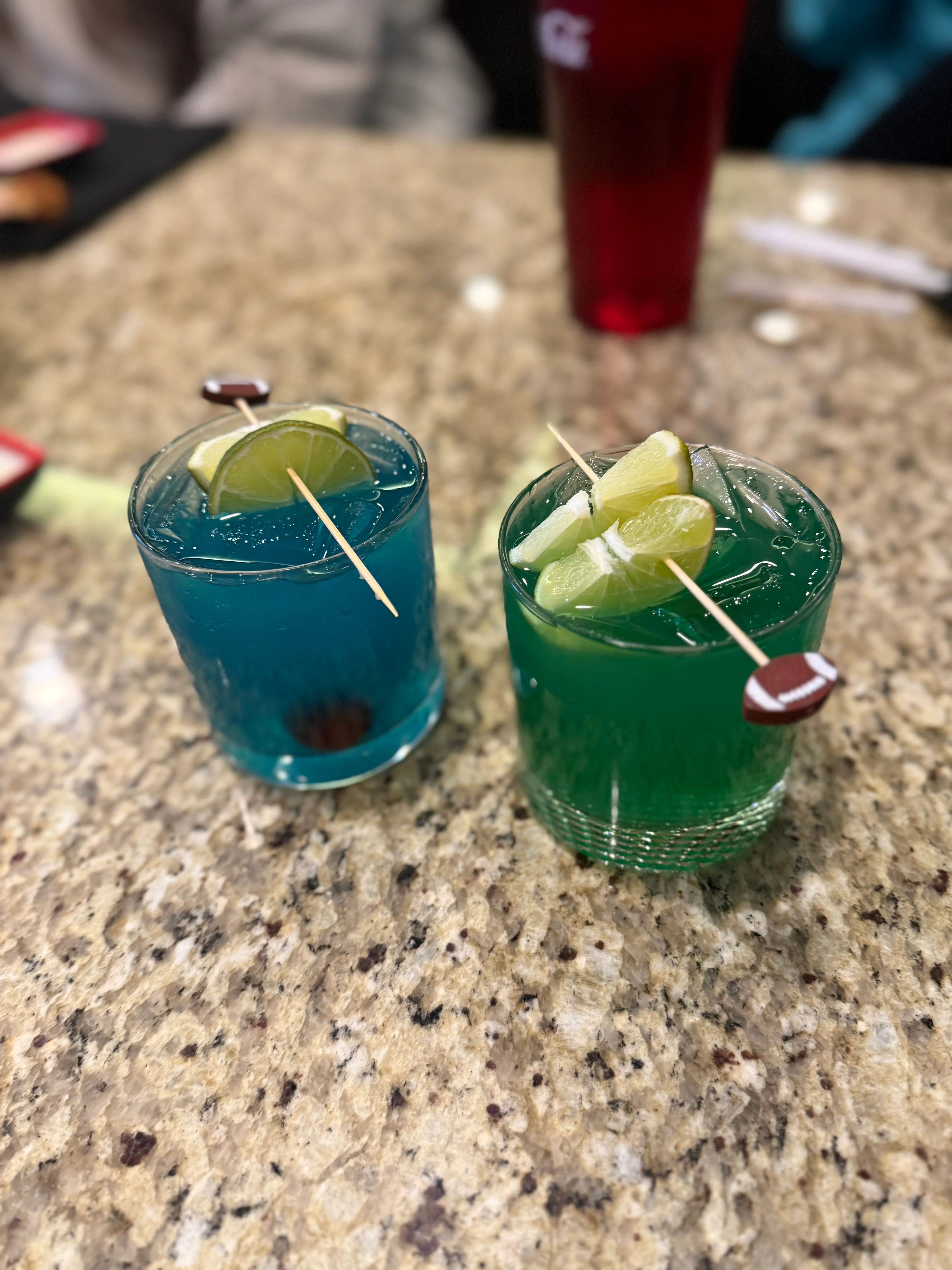 Colorful cocktails with lime garnishes on a granite bar top